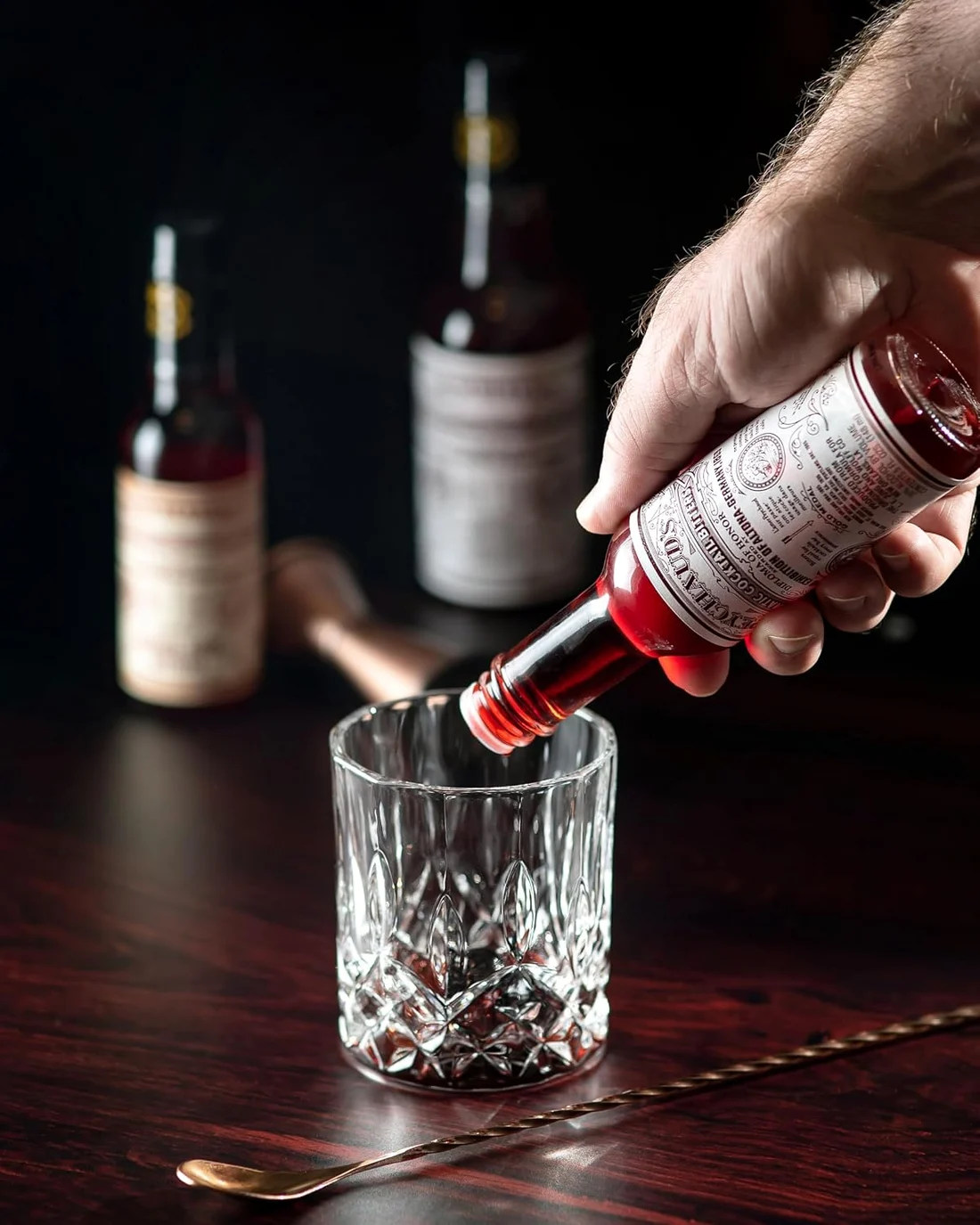 Aromatic bitters being dashed into a glass