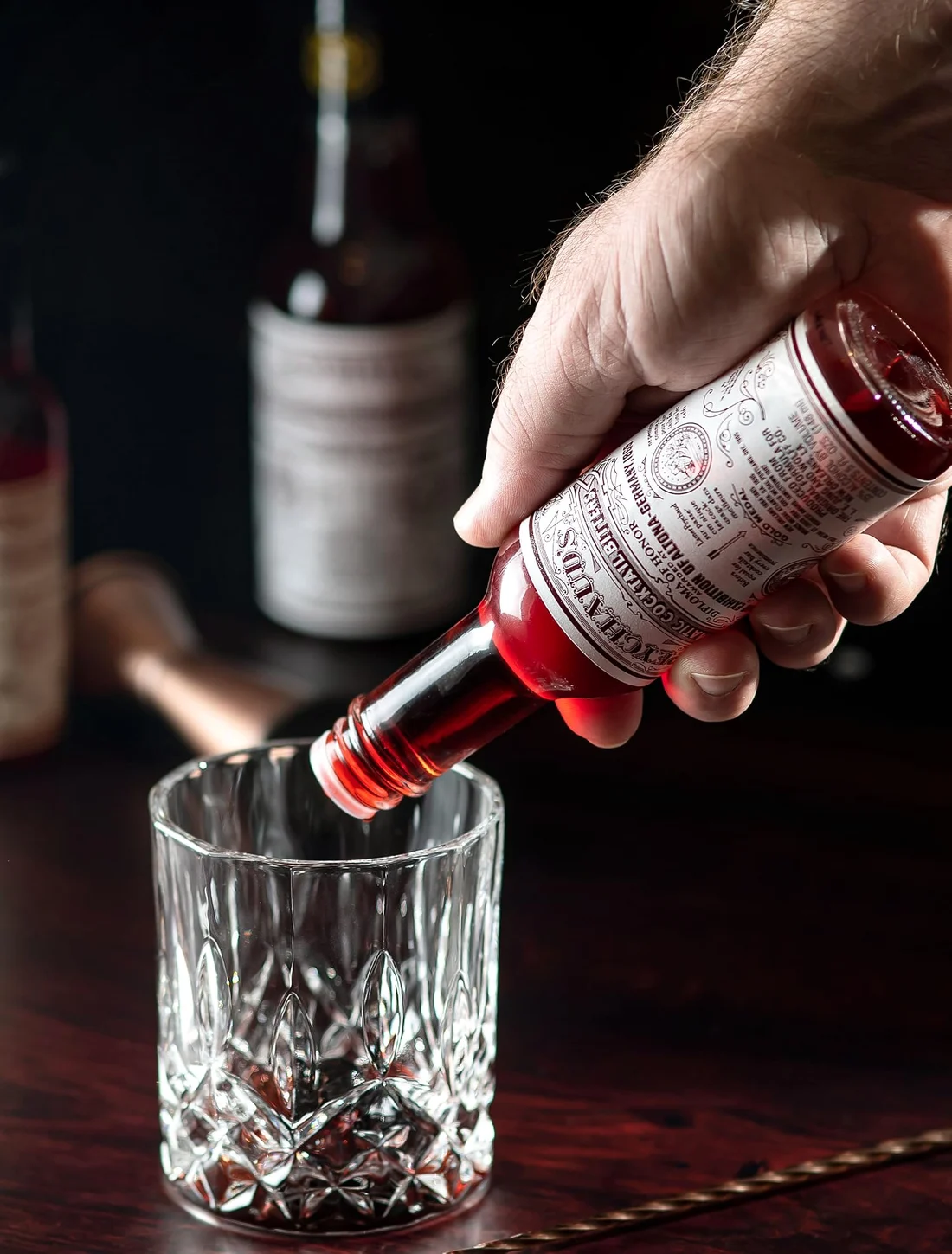 Aromatic bitters being dashed into a glass